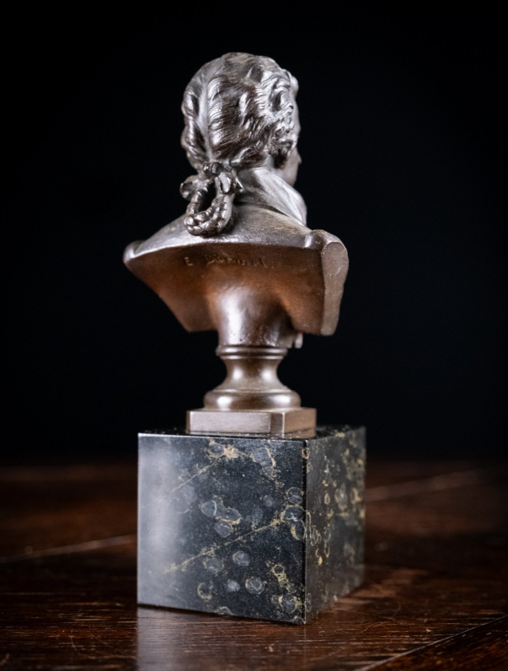 A dark patinated bronze bust of Wolfgang Amadeus Mozart mounted on a square black marble plinth. View VII