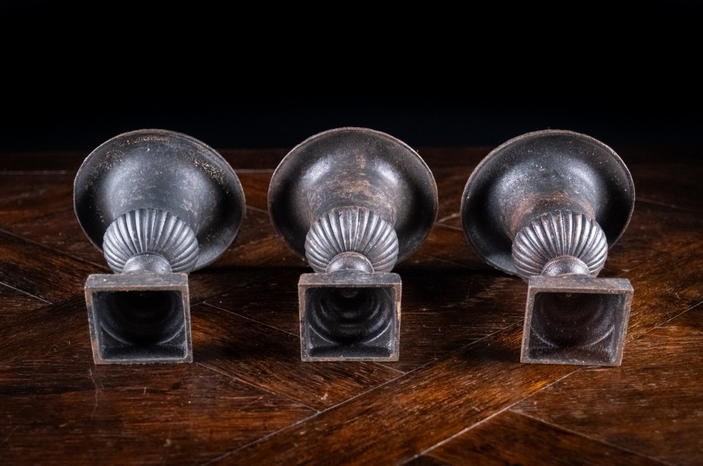 A set of three miniature cast iron urns featuring fluted campana bodies and square pedestal bases with a dark patinated finish. View VIII