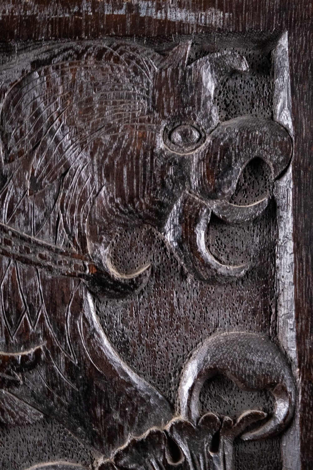 A rectangular dark oak timber panel featuring a high-relief hand carving of a crouching dragon with a feathered neck and curved tail. View III