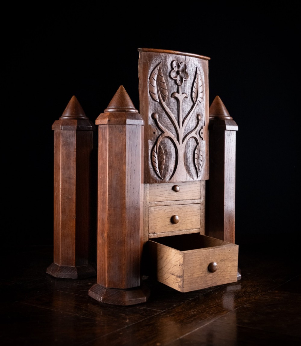 A 19th-century carved oak jewellery box designed like a castle with four corner turrets, floral relief panels, and small drawers.