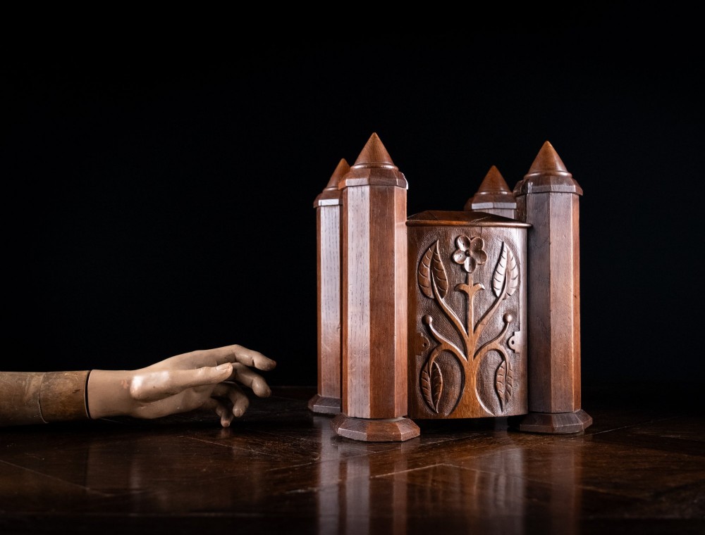 A 19th-century carved oak jewellery box designed like a castle with four corner turrets, floral relief panels, and small drawers. View III