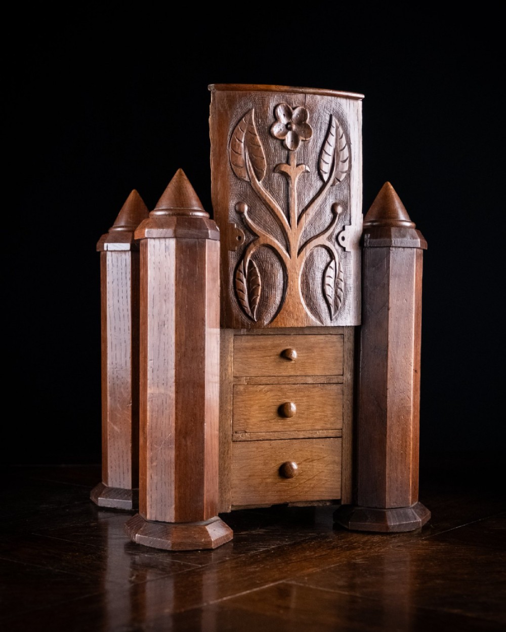 A 19th-century carved oak jewellery box designed like a castle with four corner turrets, floral relief panels, and small drawers. View IV