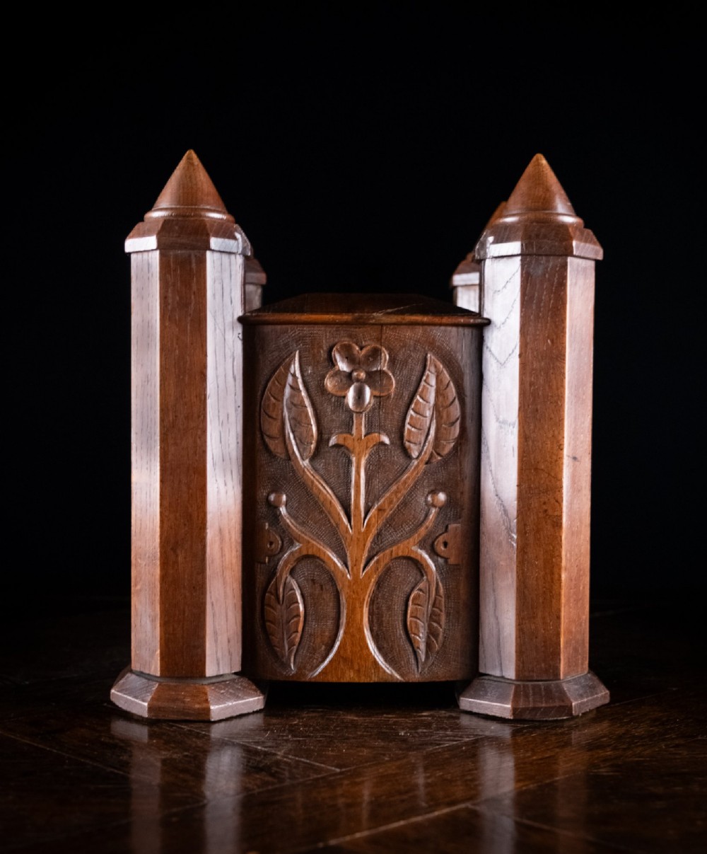 A 19th-century carved oak jewellery box designed like a castle with four corner turrets, floral relief panels, and small drawers. View V