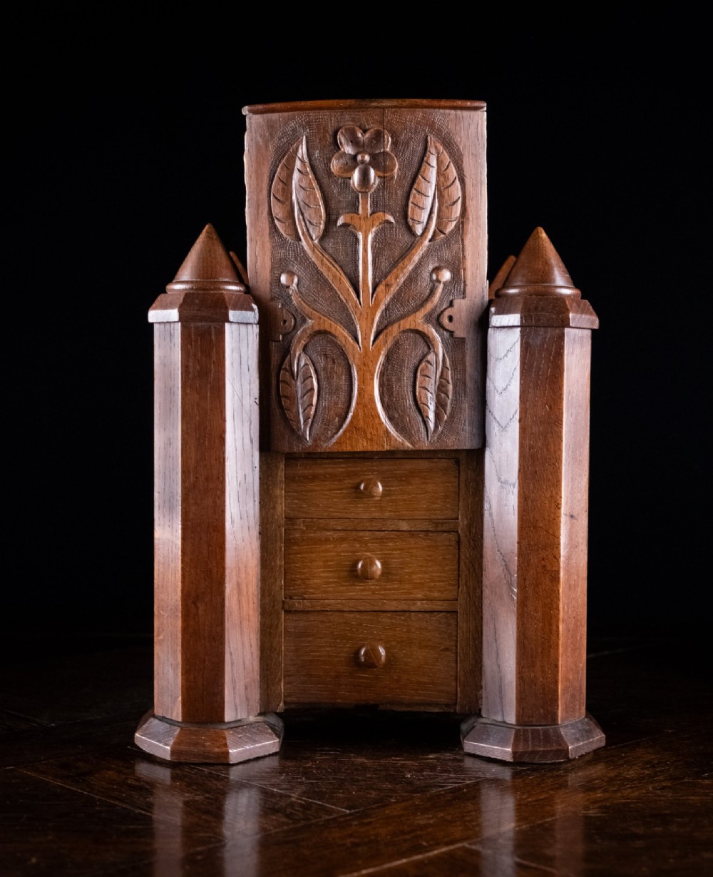 A 19th-century carved oak jewellery box designed like a castle with four corner turrets, floral relief panels, and small drawers. View VII