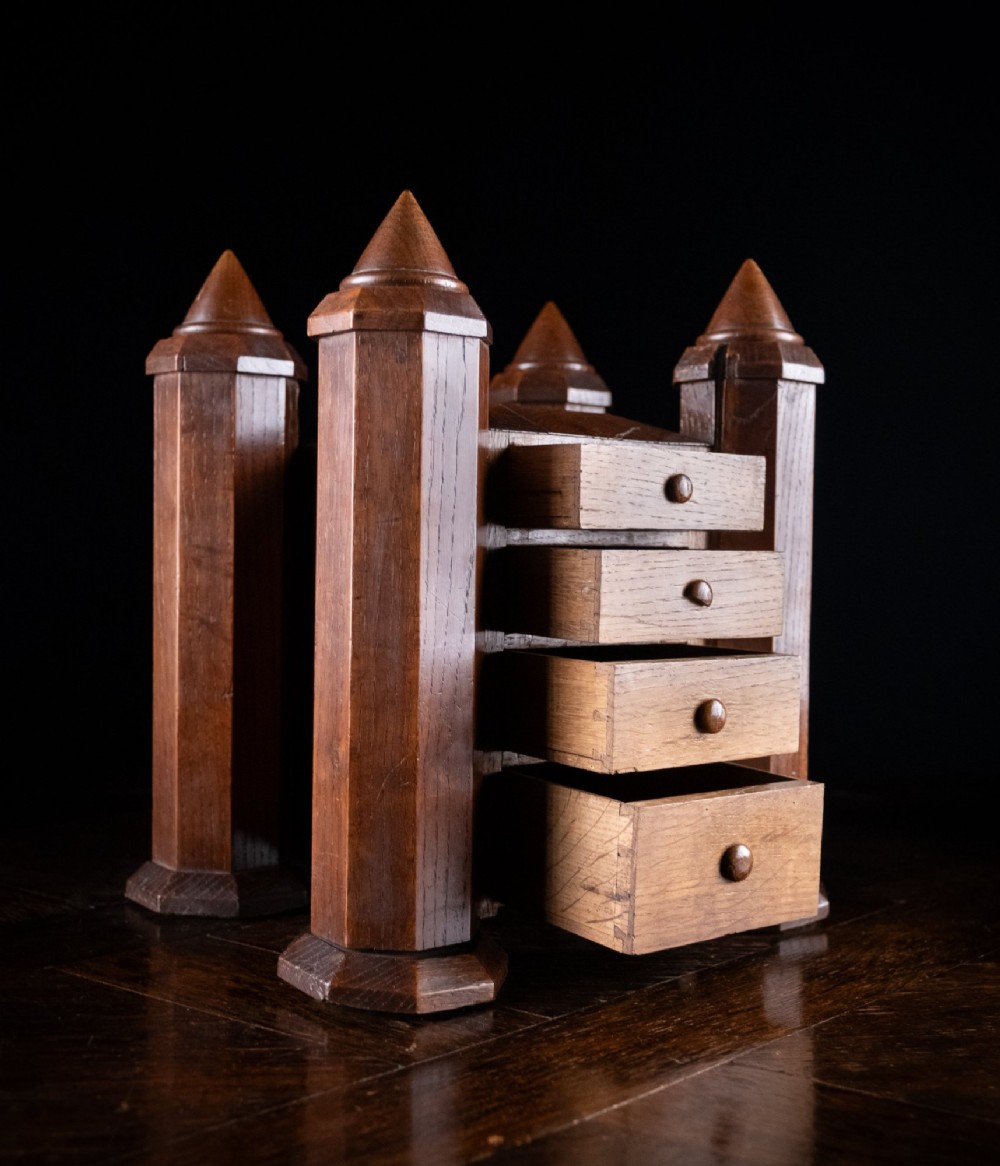 A 19th-century carved oak jewellery box designed like a castle with four corner turrets, floral relief panels, and small drawers. View IX