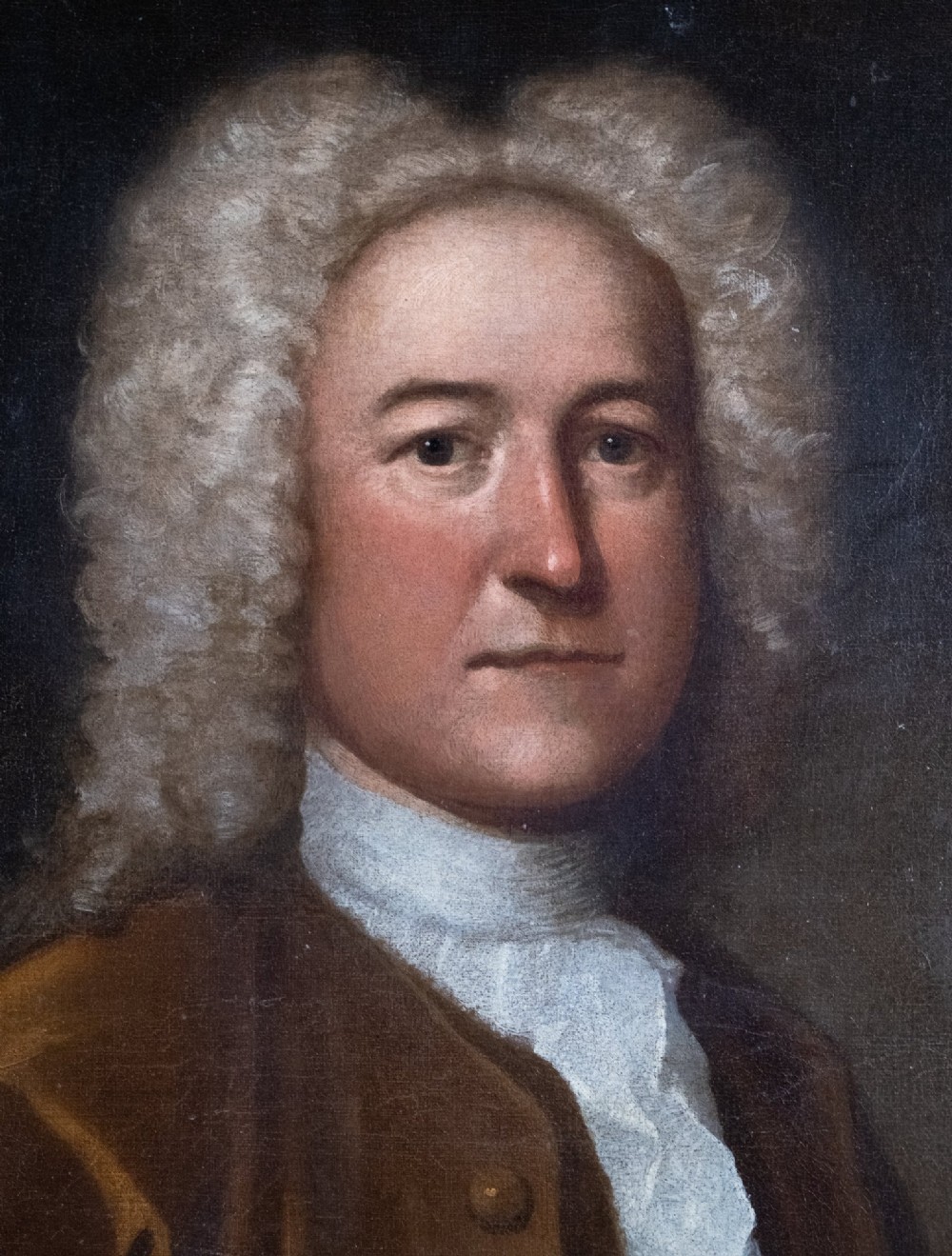 An early eighteenth-century oil portrait of a gentleman in a wig and brown coat with his hand resting on a skull. View II