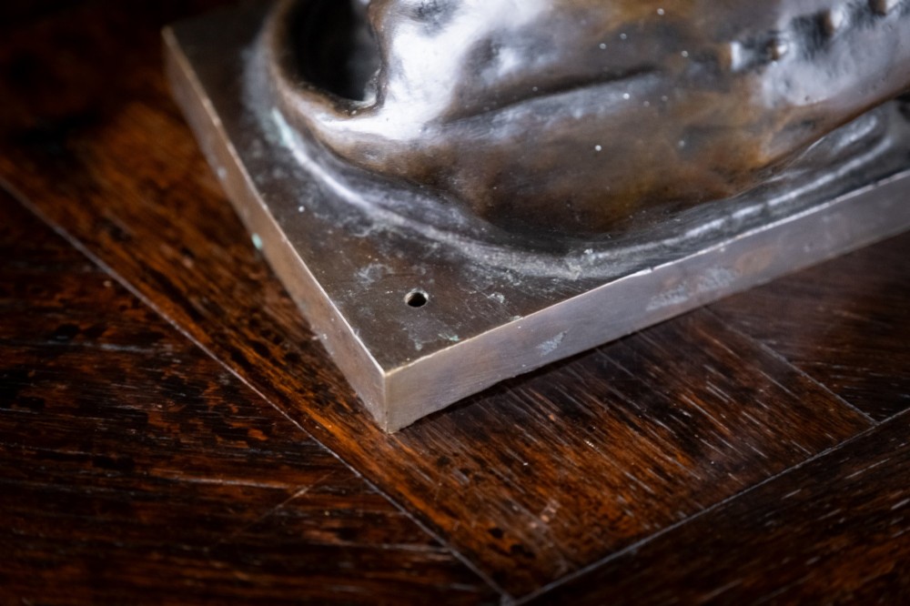 A dark brown patinated bronze sculpture depicting a recumbent sleeping lion resting its head on an integrated rectangular base. View XI