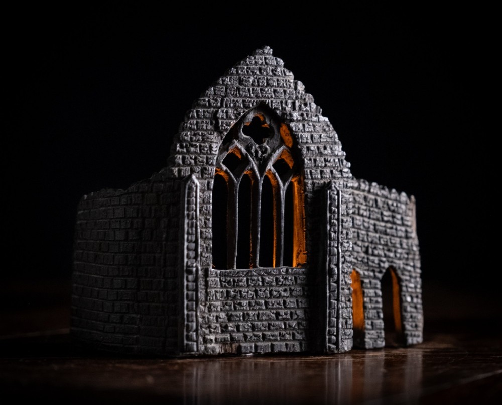 A dark hand-carved bog oak miniature representing a Gothic abbey architectural ruin with a tracery window and relief masonry wall. View II