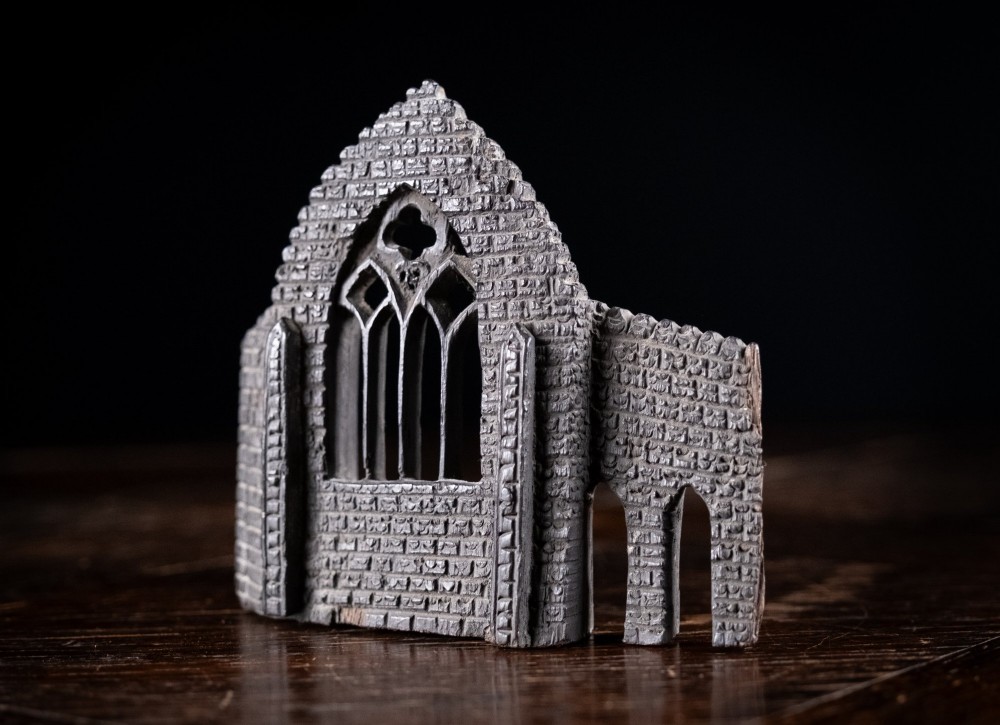 A dark hand-carved bog oak miniature representing a Gothic abbey architectural ruin with a tracery window and relief masonry wall. View IV
