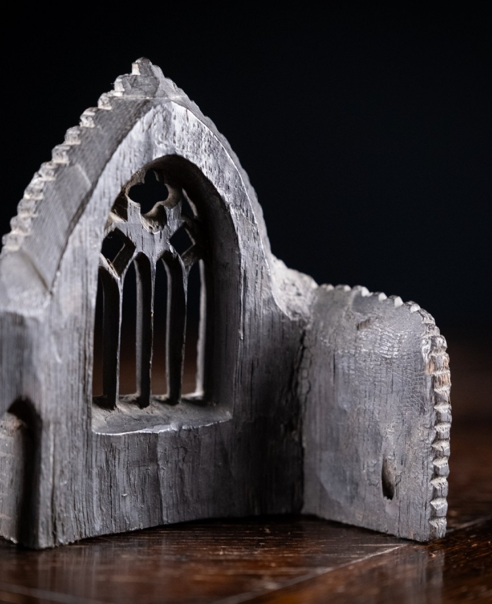 A dark hand-carved bog oak miniature representing a Gothic abbey architectural ruin with a tracery window and relief masonry wall. View VIII