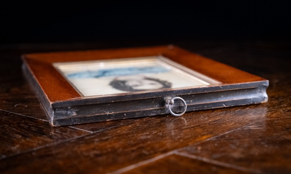 An early 19th-century watercolour portrait miniature depicting a young girl with dark curls in a blue dress, displayed in a dark wood frame. View VII