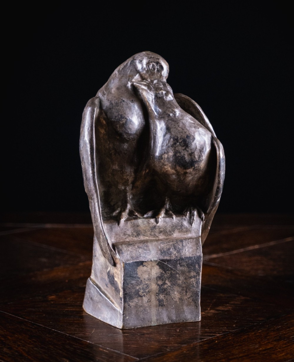 A patinated nickel bronze sculpture depicting two pigeons embracing atop a geometric plinth.