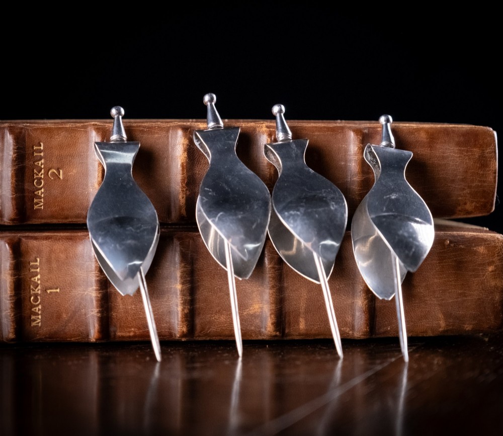 A set of four Art Deco sterling silver lemon wedge squeezers with pointed spikes and hallmarked hinged pads. View IV