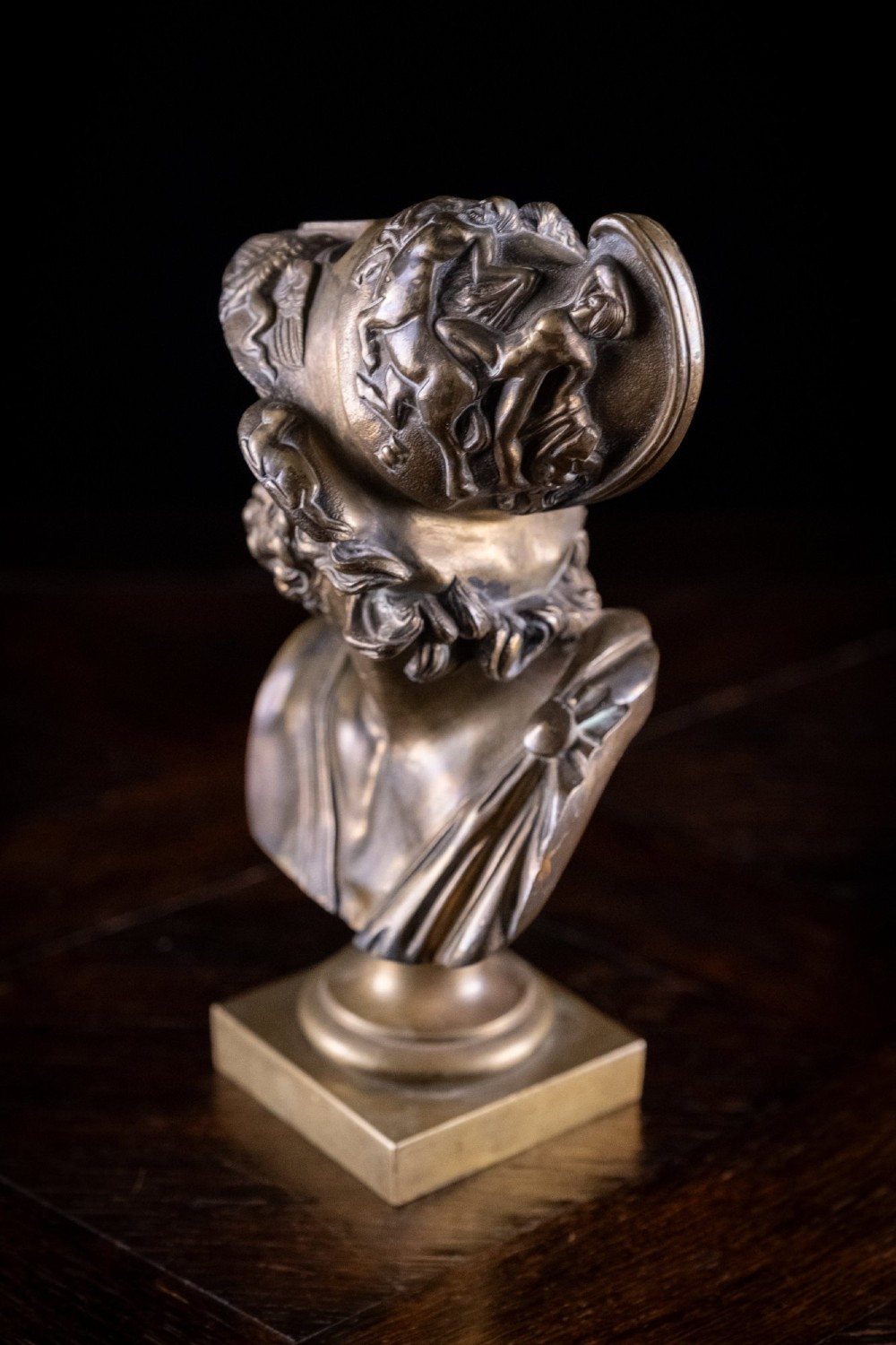 A profile view of a gilt bronze classical bust depicting a bearded warrior in a relief helmet set on a square pedestal base. View V