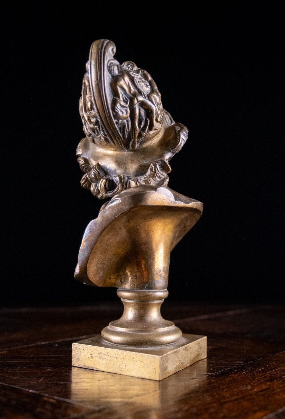 A profile view of a gilt bronze classical bust depicting a bearded warrior in a relief helmet set on a square pedestal base. View IX