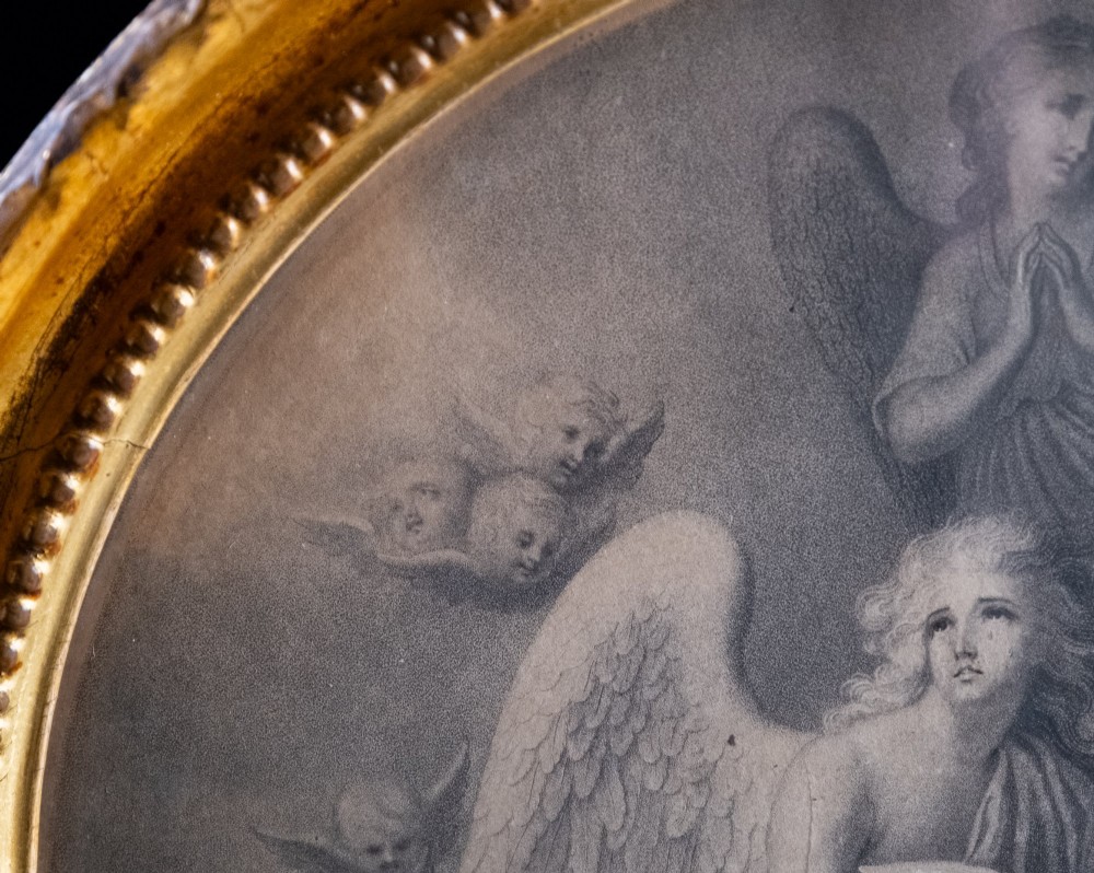 An 18th-century monochrome circular engraving depicting winged angels amidst clouds, presented within a carved giltwood circular frame. View V