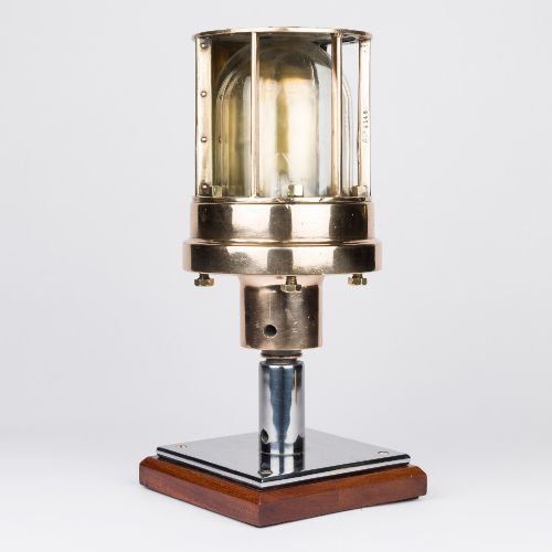 fig 1. A polished brass submarine steaming light featuring a clear glass dome encased in a protective metal cage, mounted on a chrome stem and wooden plinth.