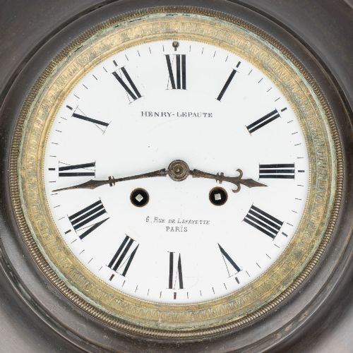 fig 1. A circular dark bronze French wall clock designed in the shape of a pocket watch with a white enamel dial and Roman numerals.