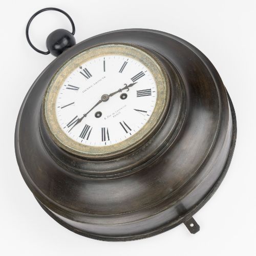fig 2. A circular dark bronze French wall clock designed in the shape of a pocket watch with a white enamel dial and Roman numerals.