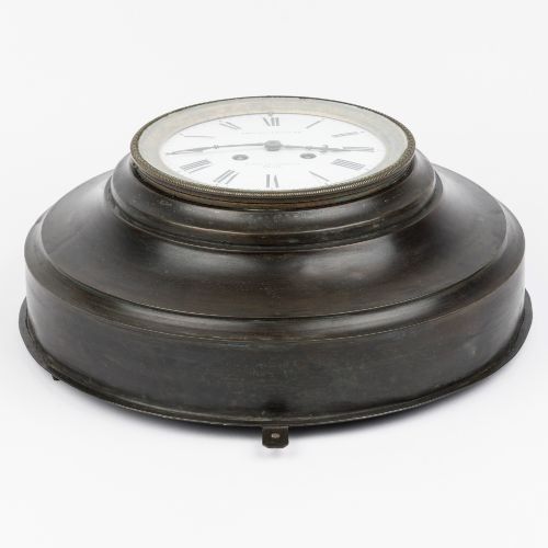 fig 3. A circular dark bronze French wall clock designed in the shape of a pocket watch with a white enamel dial and Roman numerals.