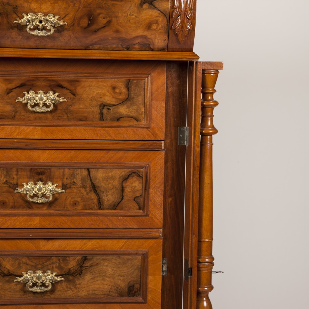 A tall 19th-century burr walnut chest of six drawers featuring ornate gilded brass handles, flanking turned pilasters, and bun feet. View V