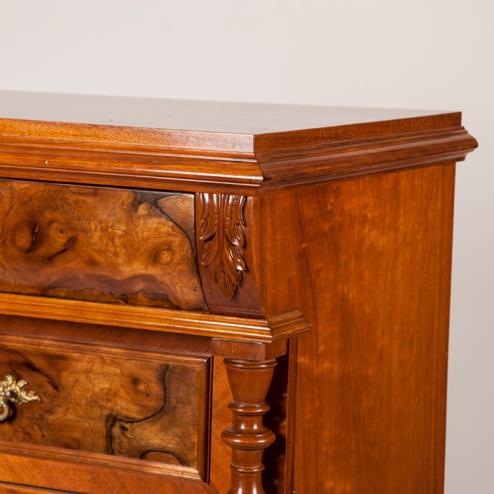 A tall 19th-century burr walnut chest of six drawers featuring ornate gilded brass handles, flanking turned pilasters, and bun feet. View VI