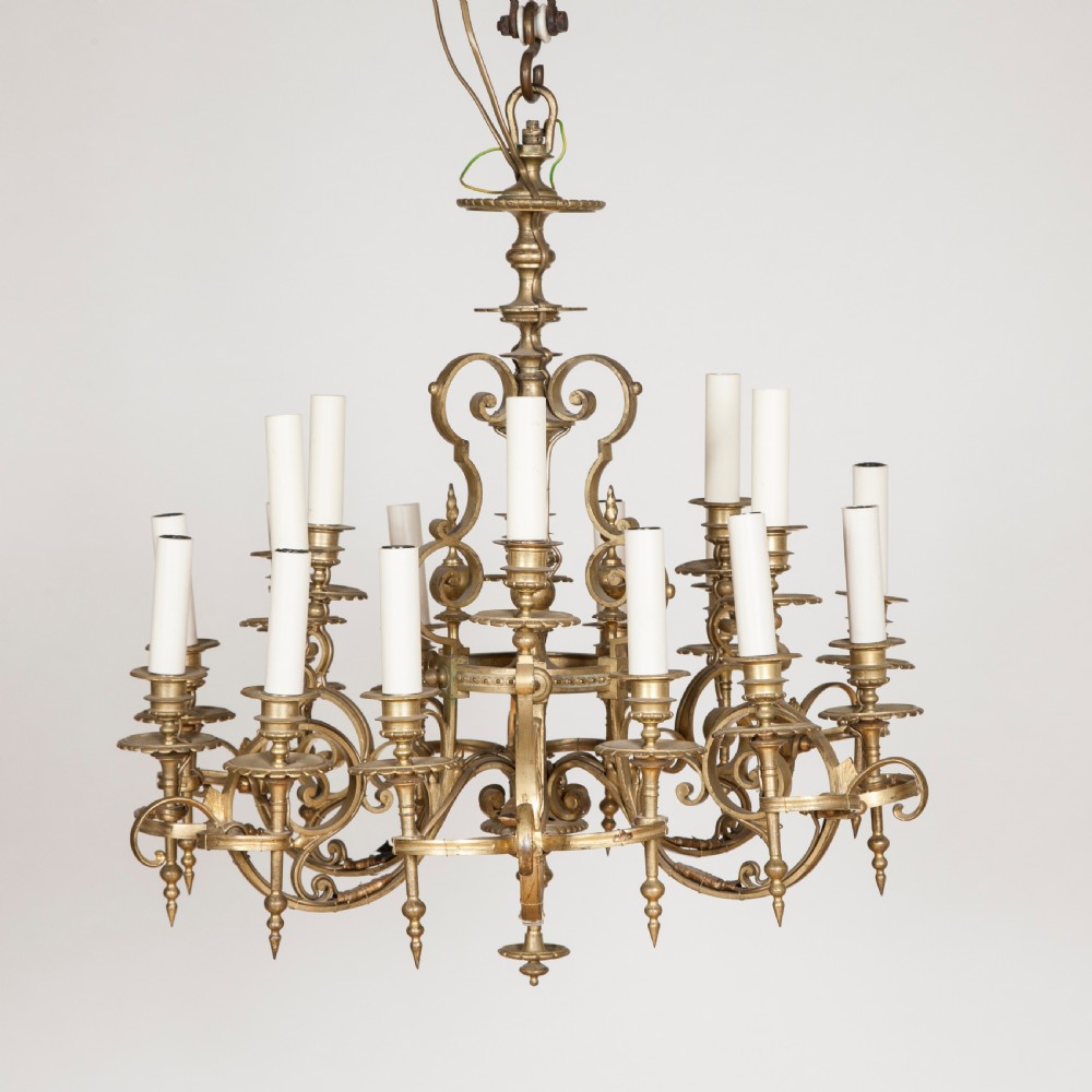 A late nineteenth-century gilt bronze eighteen-light chandelier featuring tiered scrollwork arms and faux candle sleeves.