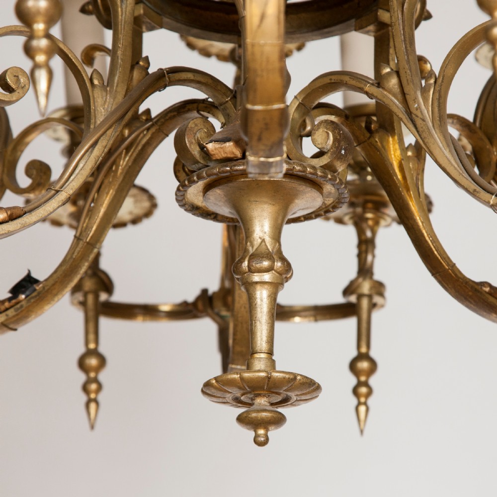 A late nineteenth-century gilt bronze eighteen-light chandelier featuring tiered scrollwork arms and faux candle sleeves. View V