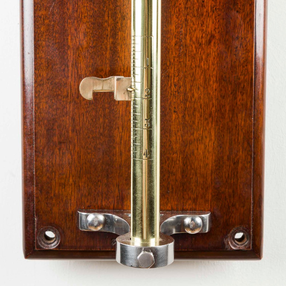 A wall-mounted antique Goodbrand & Co brass and steel yarn testing instrument mounted on a rectangular mahogany board with a circular dial scale. View IV
