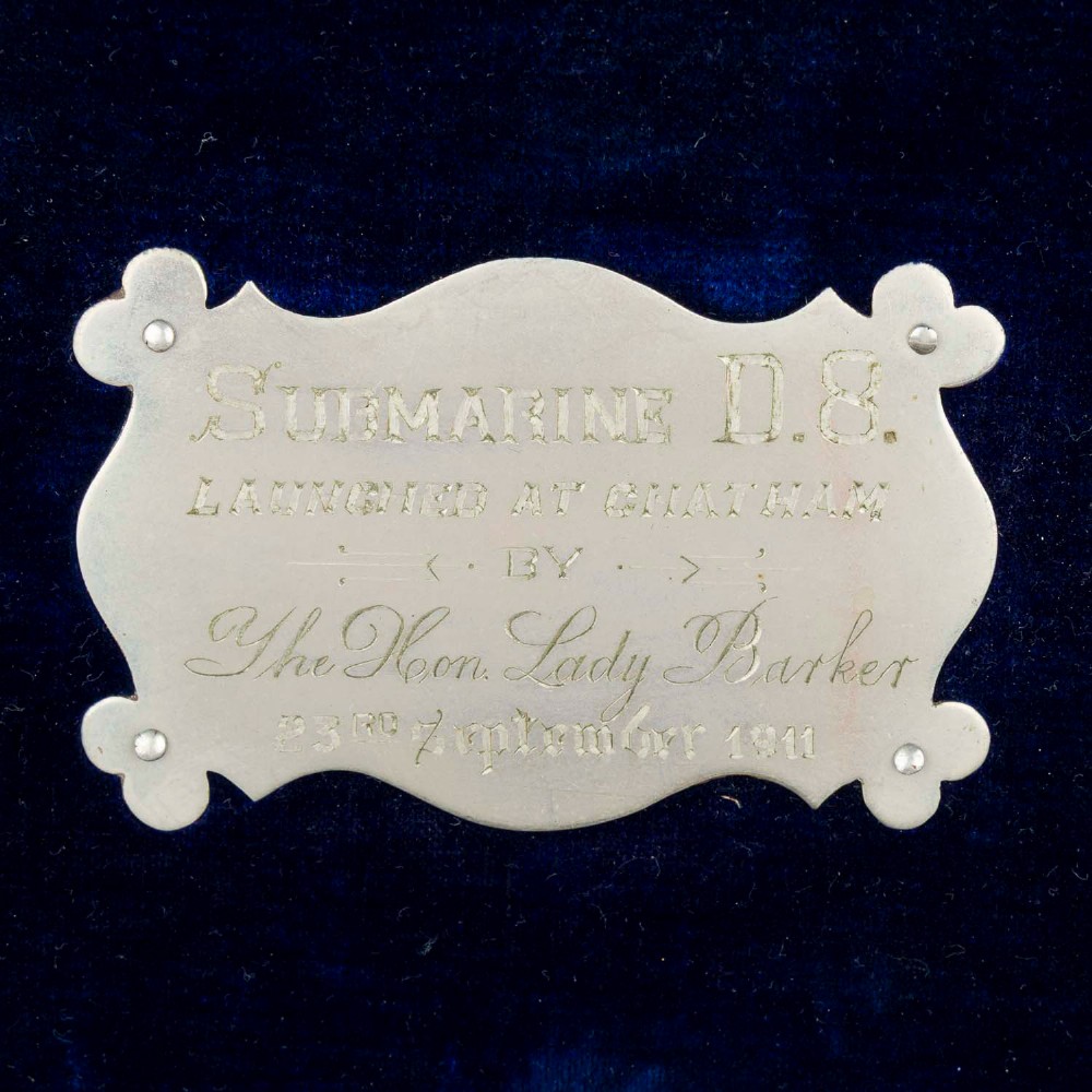 An open Edwardian carved oak presentation casket lined in navy blue velvet, containing a carved wooden ceremonial mallet and chisel set with an engraved silver plaque. View II