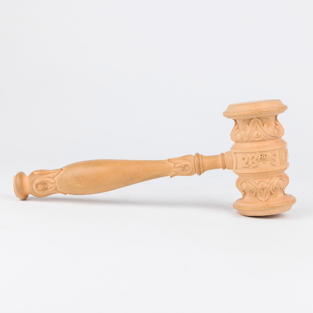 An open Edwardian carved oak presentation casket lined in navy blue velvet, containing a carved wooden ceremonial mallet and chisel set with an engraved silver plaque. View VI