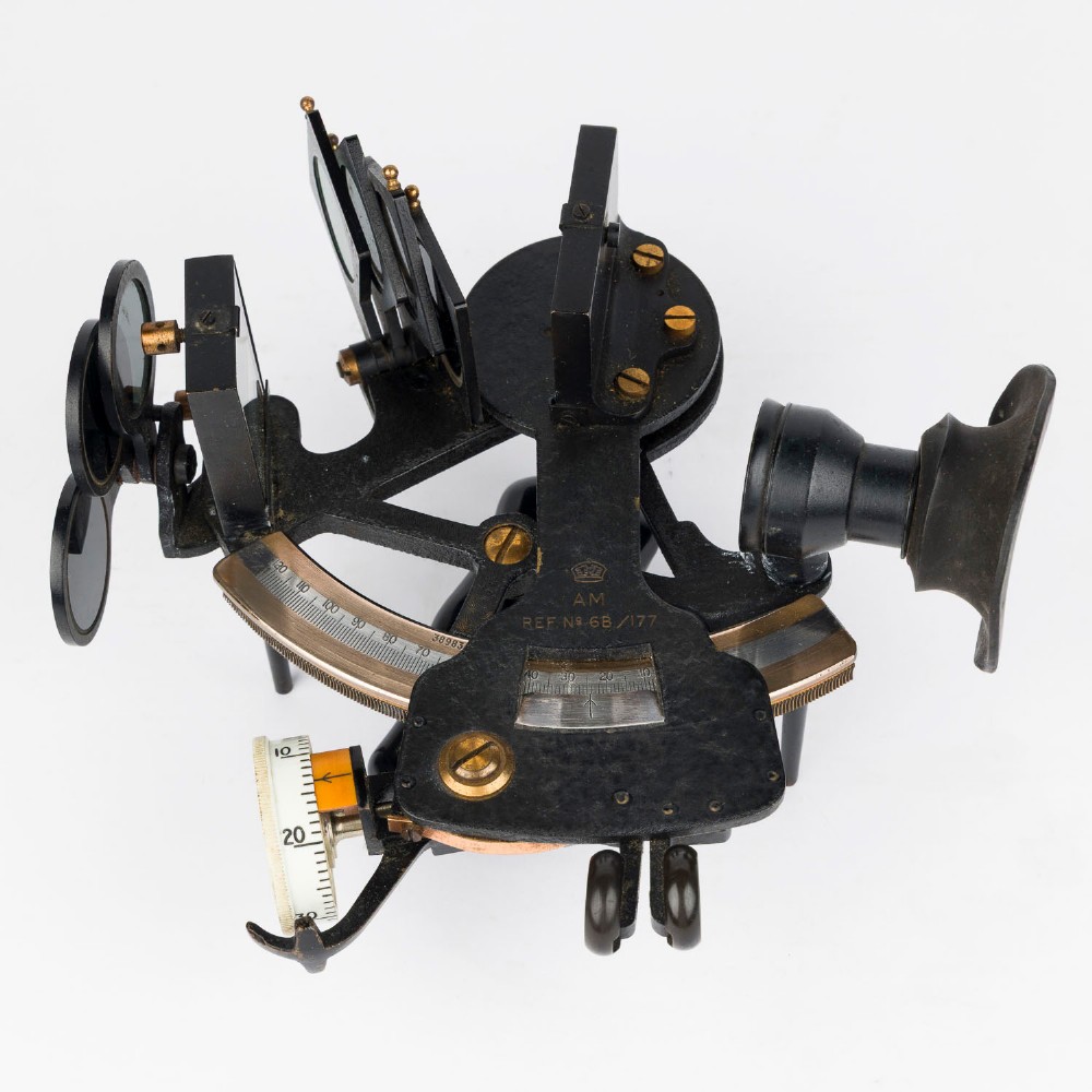 A mid-20th-century black metal and brass RAF bubble sextant with optical lenses, fine adjustment dials, and an engraved Air Ministry stamp.
