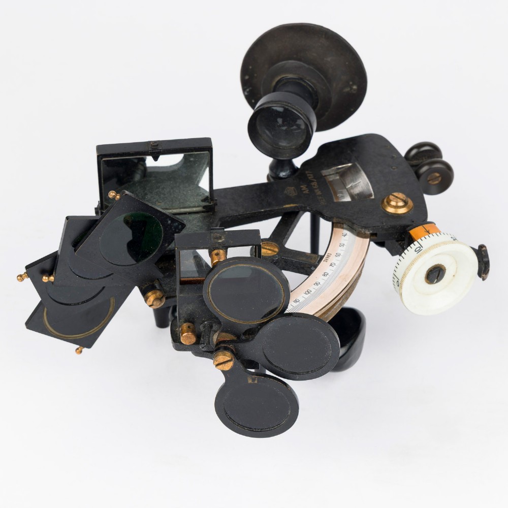 A mid-20th-century black metal and brass RAF bubble sextant with optical lenses, fine adjustment dials, and an engraved Air Ministry stamp. View II