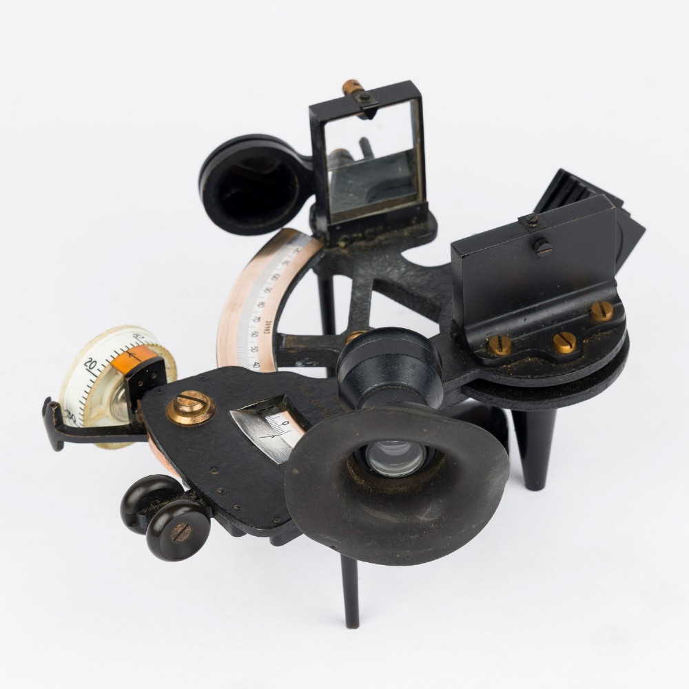 A mid-20th-century black metal and brass RAF bubble sextant with optical lenses, fine adjustment dials, and an engraved Air Ministry stamp. View III