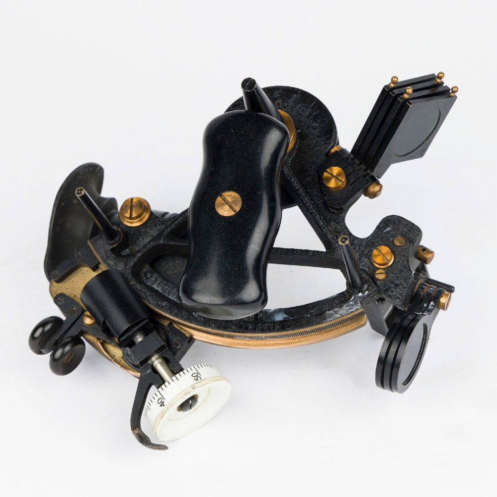 A mid-20th-century black metal and brass RAF bubble sextant with optical lenses, fine adjustment dials, and an engraved Air Ministry stamp. View V