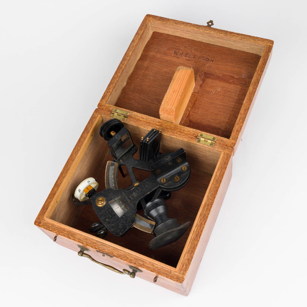 A mid-20th-century black metal and brass RAF bubble sextant with optical lenses, fine adjustment dials, and an engraved Air Ministry stamp. View VII
