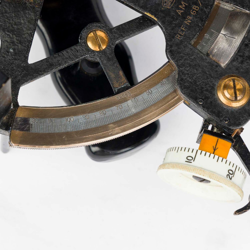A mid-20th-century black metal and brass RAF bubble sextant with optical lenses, fine adjustment dials, and an engraved Air Ministry stamp. View VIII