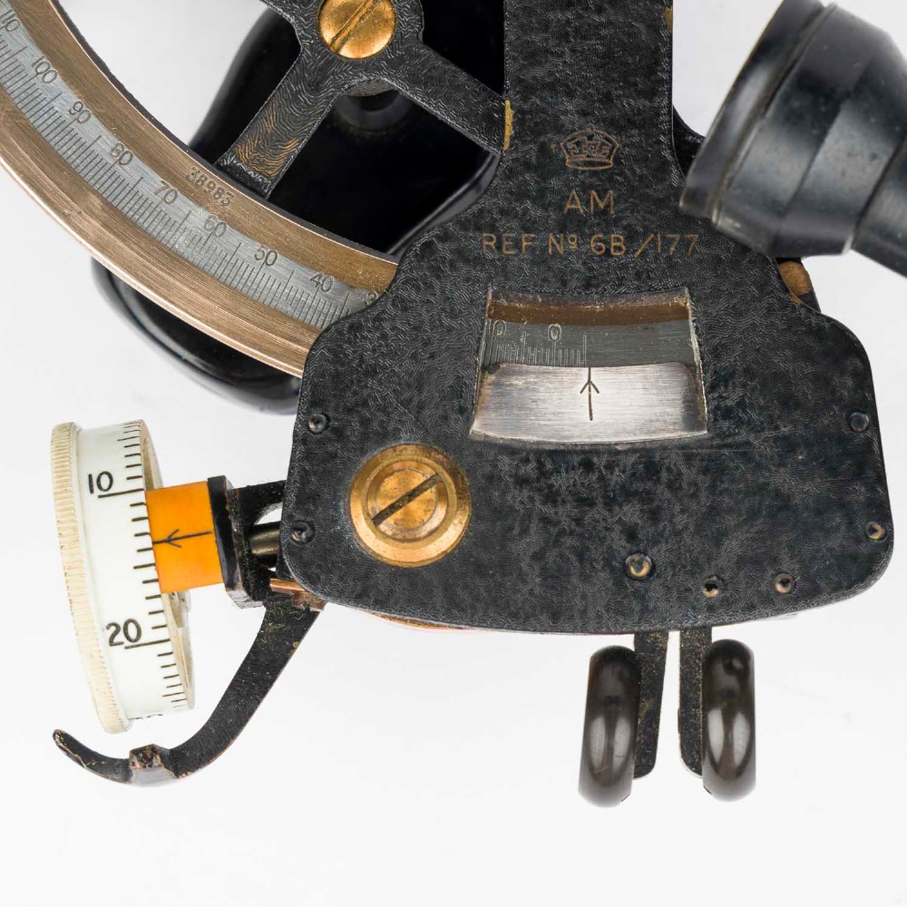 A mid-20th-century black metal and brass RAF bubble sextant with optical lenses, fine adjustment dials, and an engraved Air Ministry stamp. View IX