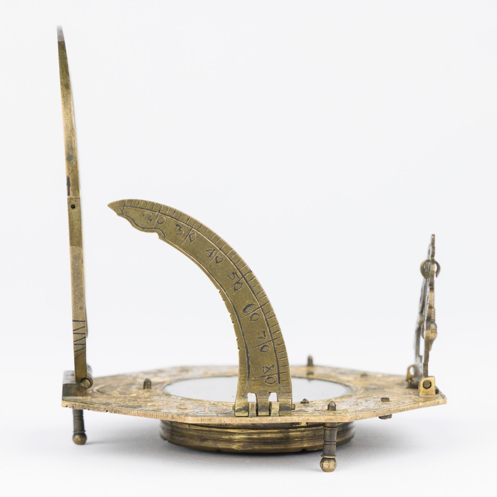 An 18th-century engraved brass octagonal pocket sundial with an inset glass-covered compass, an adjustable latitude arc, and a hinged hour ring. View II