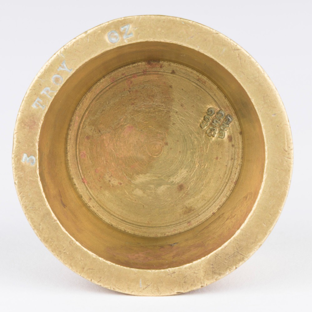 A set of eight graduated cylindrical brass nesting cup weights arranged in two loose rows on a plain white surface. View XI