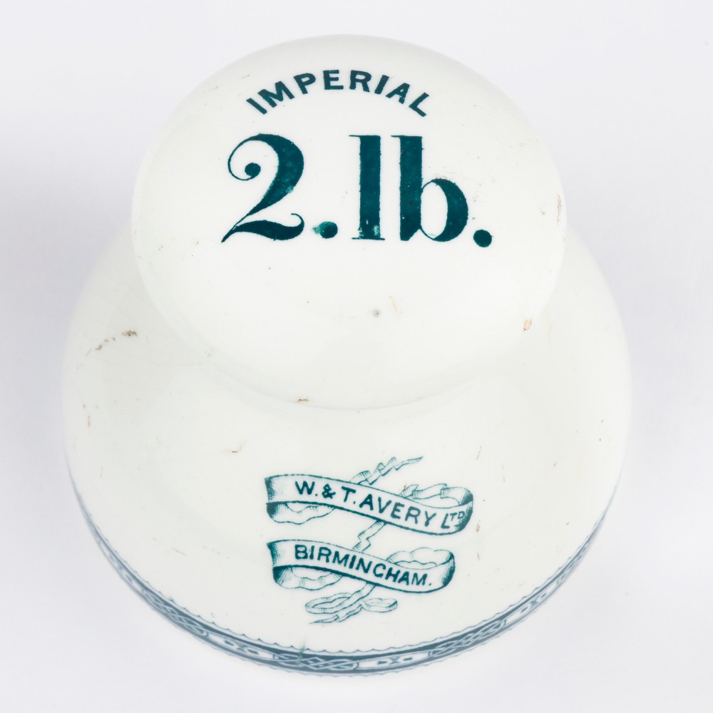 A pair of white glazed ceramic shop scale weights decorated with blue transfer-printed text and scroll borders for W and T Avery Birmingham. View II