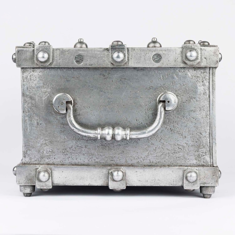 A heavy rectangular metal strongbox featuring riveted steel straps, raised studs, an embossed coat of arms, and maker plaques. View IV
