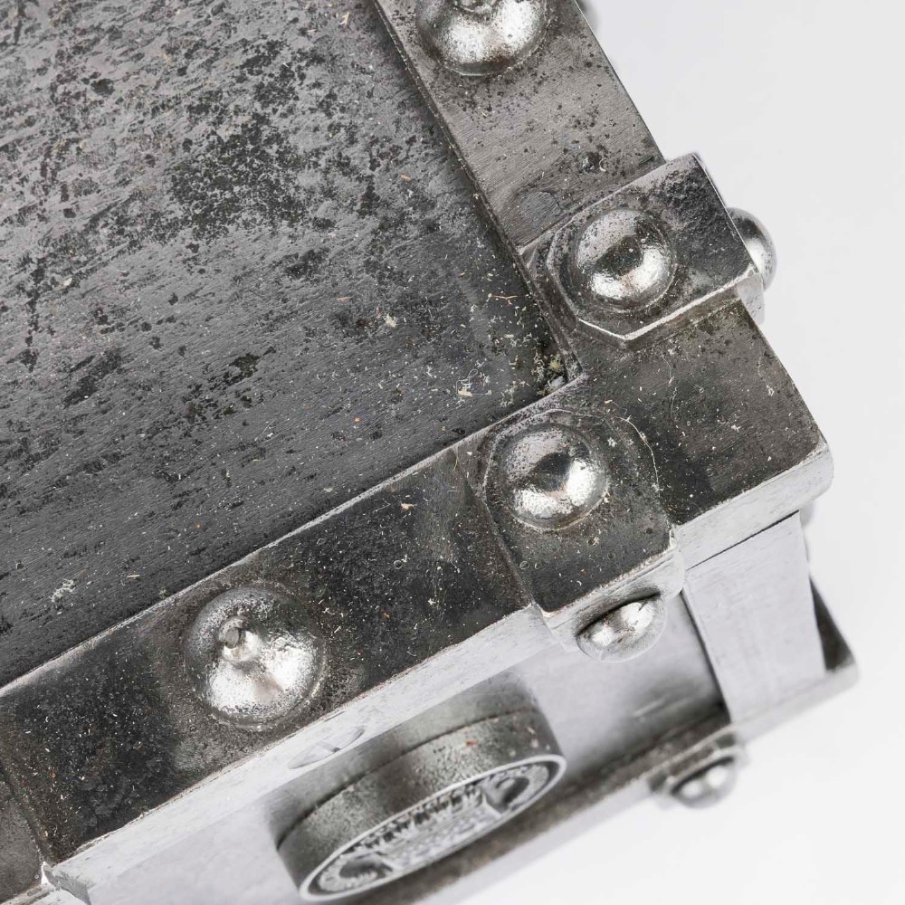 A heavy rectangular metal strongbox featuring riveted steel straps, raised studs, an embossed coat of arms, and maker plaques. View XI