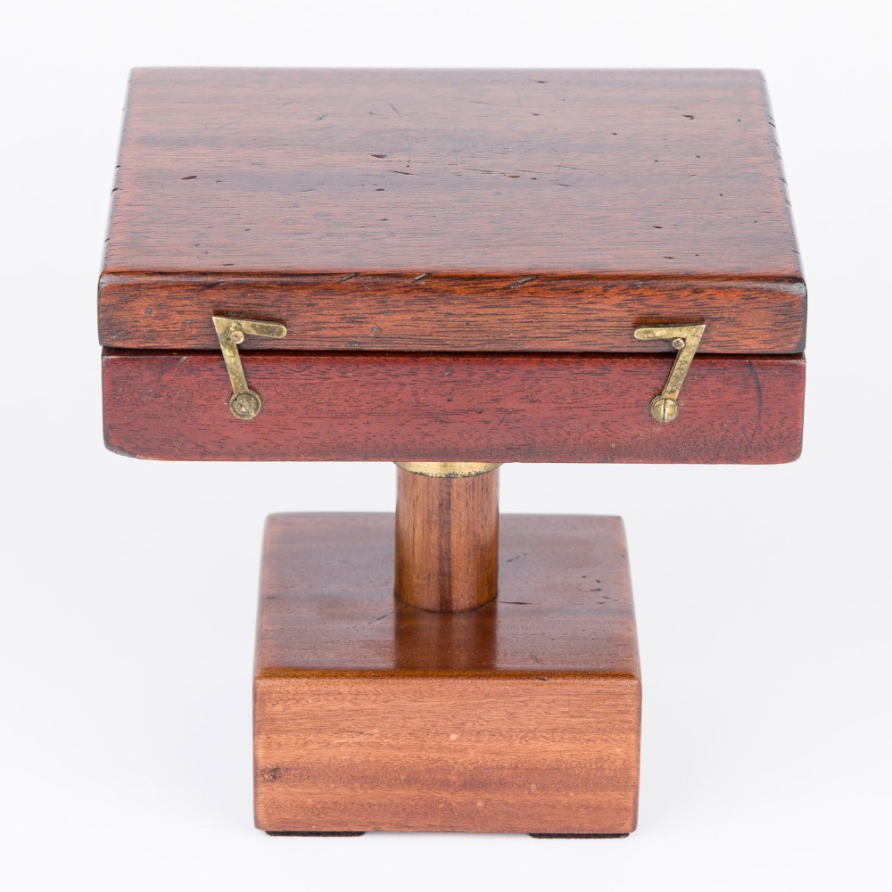 An antique mahogany cased surveyor compass with folding brass sight vanes and a circular glass-covered needle face, mounted on a wooden pedestal base. View VIII