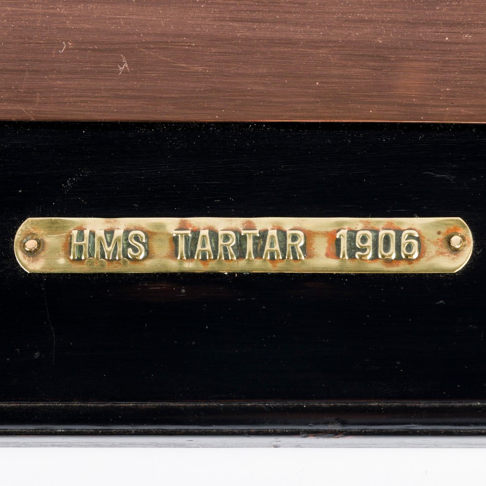 A rectangular black lacquered wooden plaque displaying a copper cutout profile of HMS Tartar 1906 with a small brass title tag below. View II
