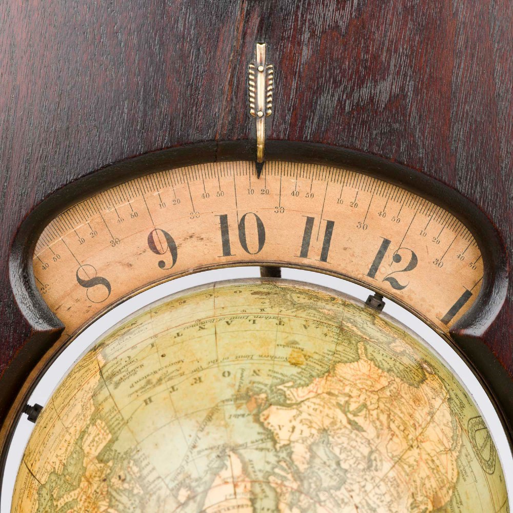 A dark mahogany Timby solar timepiece featuring an embedded central globe beneath a curved hour scale and brass finials. View V
