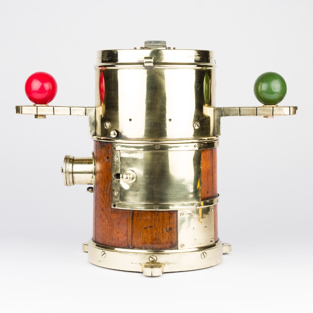 A polished brass and mahogany submarine binnacle featuring a hinged hood with carrying handle, a glass viewing lens, and extended side arms holding red and green painted iron spheres. View X