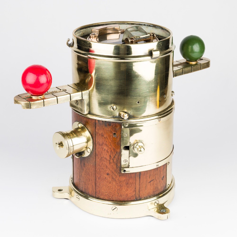 A polished brass and mahogany submarine binnacle featuring a hinged hood with carrying handle, a glass viewing lens, and extended side arms holding red and green painted iron spheres. View XI