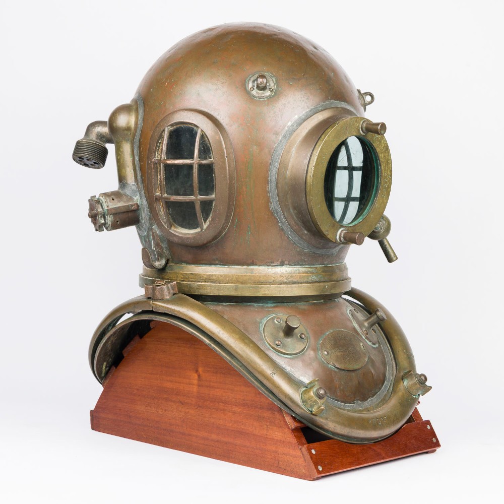 An antique Siebe Gorman copper and brass deep-sea diving helmet with a central circular viewport and lateral window grilles. View II