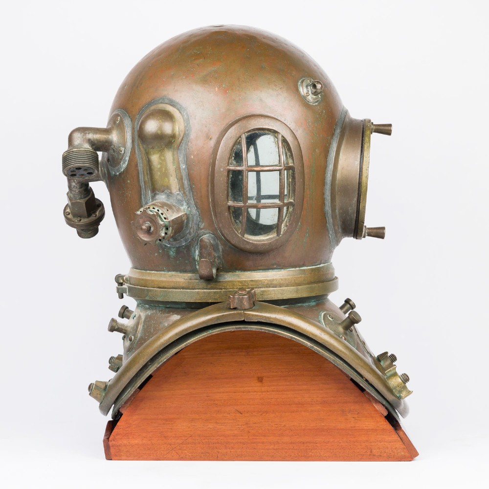 An antique Siebe Gorman copper and brass deep-sea diving helmet with a central circular viewport and lateral window grilles. View III